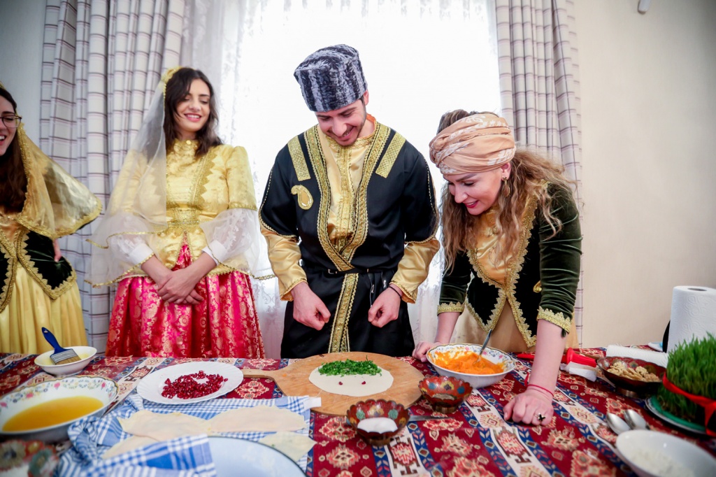George-Deek-and-his-wife-Anna-to-his-right-learning-to-cook-Azerbaijani-traditional-food-during-major-holiday-of-Novruz-at-Baku-home-of-Fakhranda-Hasanzadeh-woman-leaning-March-20221.jpg